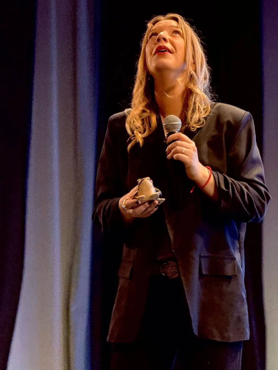Laura Deghilage en conférence, micro à la main, le regard levé